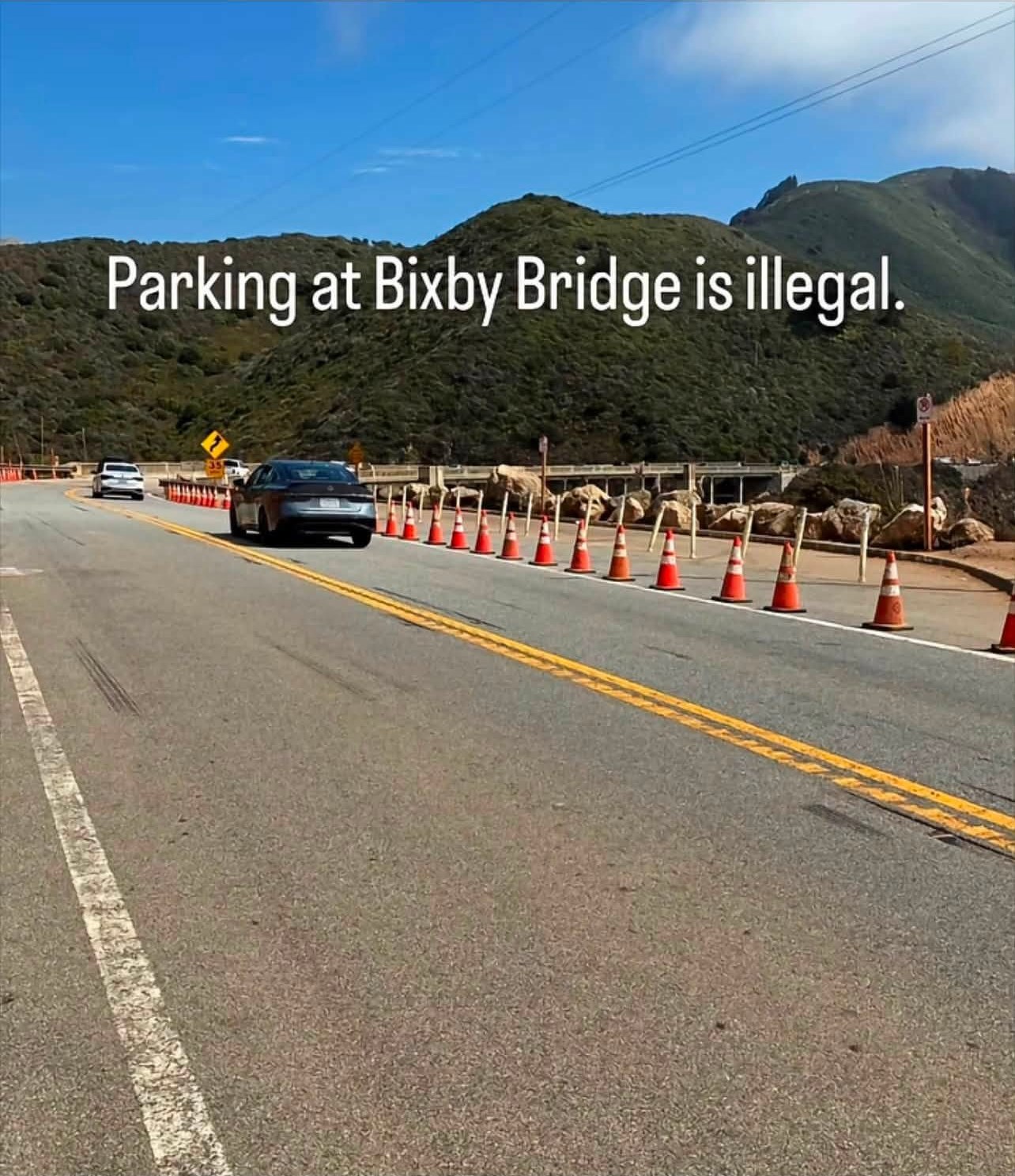 Highway 1 at Bixby Bridge with the northbound shoulder closed off by a line of traffic cones and a no-parking sign.